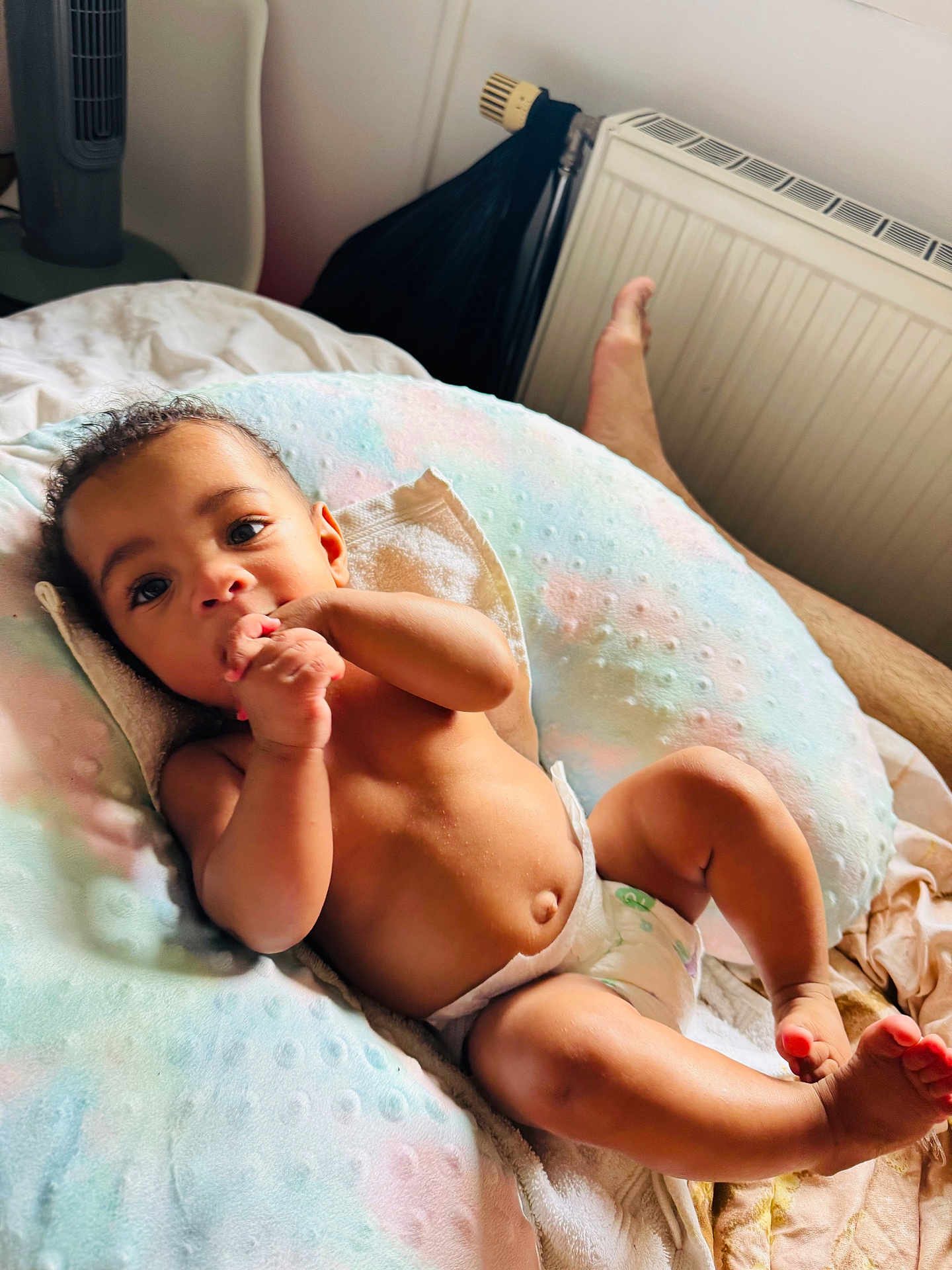 Isïah participe au concours pour gagner de l'argent avec cette photo : baby, infant, diaper, cushion, pastel_colors, hand, fingers, curly_hair, skin, lying_down, indoor, blanket, adult_leg, relaxation, comfort, portrait, child, person, cute, nurturing