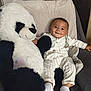 baby, child, smiling, plush_toy, panda, chair, white_clothing, striped_pants, socks, cute, indoor, cozy, soft_texture, happy, portrait, infant, cuddly, relaxed, seated, toy