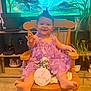 Amalya participe au concours pour gagner de l'argent avec cette photo : angel_figurine, baby, child, cushion, cute, floor, footwearless, happy, home_decor, indoor, milestone_sign, person, plant, purple_dress, rocking_chair, smiling, television, waterfall, waving_hand, wooden_furniture