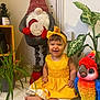 Amalya a rejoint le concours — aidez-le/la à gagner de superbes lots ! baby, child, colorful, cute, decor, feet, gnome, happy, headband, home, indoor, infant, parrot, plants, portrait, sitting, smiling, stuffed_toy, toy, yellow_dress