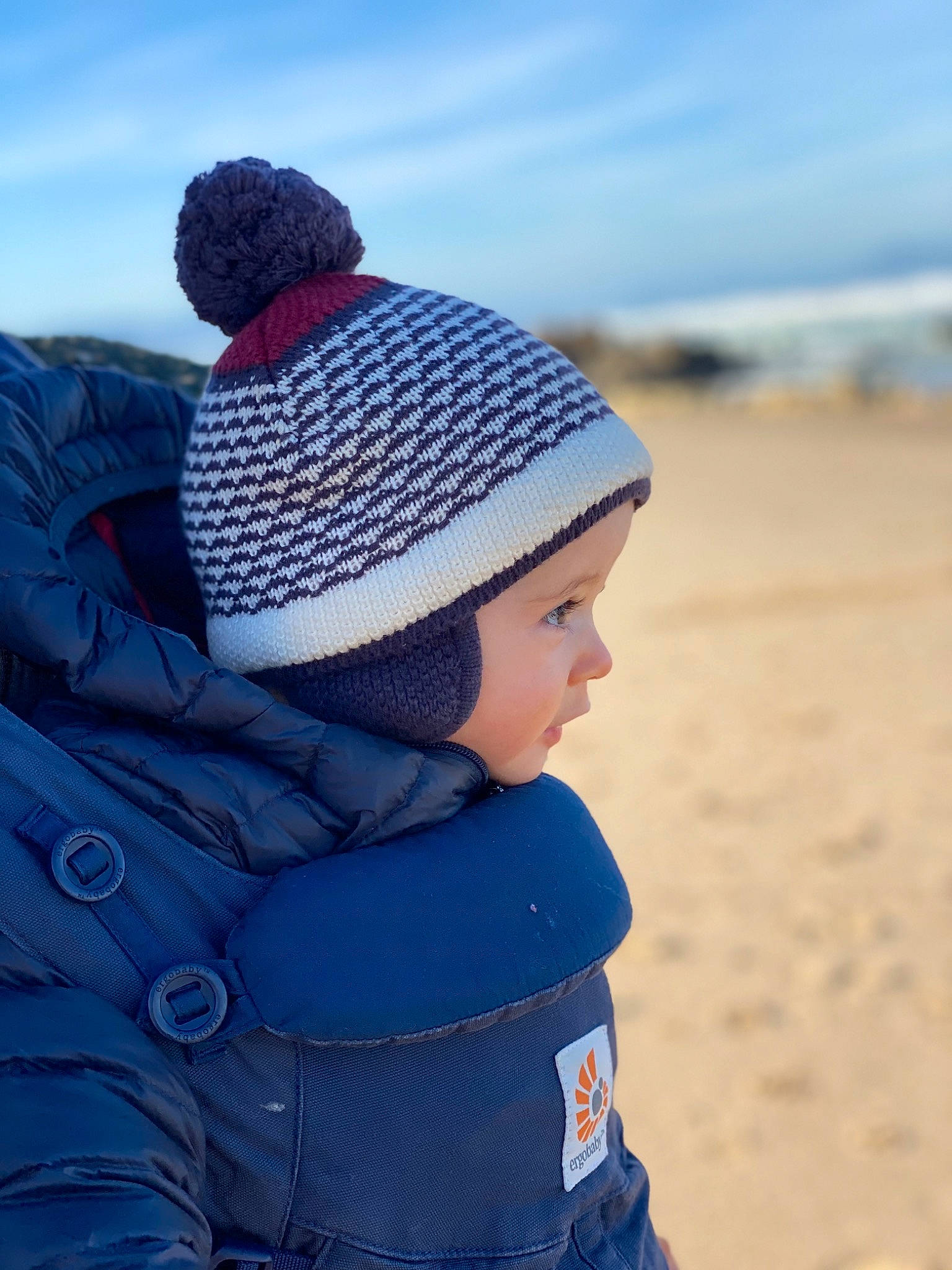 Marius participe au concours pour gagner de l'argent avec cette photo : azure, baby, beach, cap, child, electric_blue, freezing, happy, headgear, jacket, knit_cap, landscape, leisure, mammal, person, sky, toddler, travel, vertebrate, wool