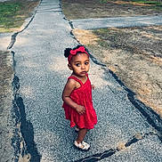 Davina is registered to the contest to win money with this photo: bow, casual_clothing, child, curious, daylight, footwear, girl, grass, nature, outdoor, pavement, person, red_dress, serious_expression, sidewalk, summer, trees, urban, walking, young_child
