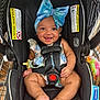 baby, car_seat, blue_bow, smiling, child, infant, harness, pacifier, shopping_cart, black, warning_label, clothing, cute, happy, headband, seatbelt, indoor, person, skin, foot