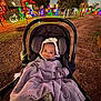 Cassie joined the competition — help win amazing prizes! baby, infant, stroller, blanket, face, smile, hood, car_seat, outdoor, night, christmas_lights, holiday_lights, festive, park, pathway, trees, illuminated, cozy, portrait, happy