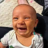 baby, smiling, infant, dinosaur_print, onesie, close_up, happy, face, head, hand, nails, teal_nails, skin, child, young, cute, expression, person, indoors, portrait