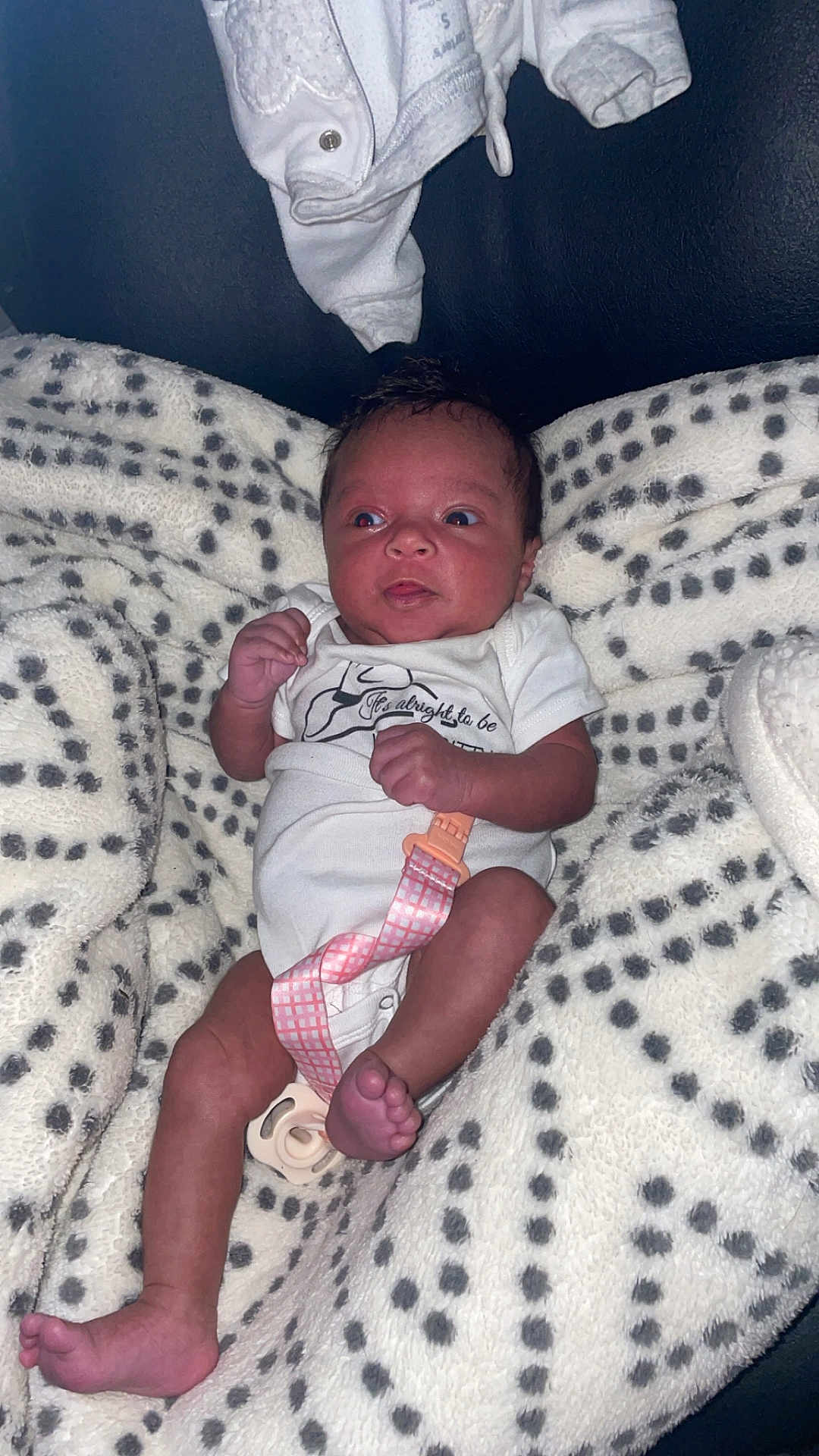 Rayellie-Marie is registered to the contest to win money with this photo: baby, blanket, clothing, comfort, cute, expression, face, foot, hand, indoor, infant, lying_down, newborn, onesie, pacifier, patterned_blanket, person, skin, soft, toddler