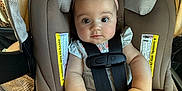 Tatum is registered to the contest to win money with this photo: baby, infant, car_seat, safety_harness, bow_headband, pink_headband, chubby_hands, big_eyes, straps, buckle, seat_label, fabric, blanket, portrait, close_up, indoors, cute, wide_eyes, sitting, child