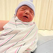 David is registered to the contest to win money with this photo: newborn, baby, infant, swaddled, blanket, hat, sleeping, hospital, wrapped, cute, child, person, soft_lighting, indoors, closeup, portrait, small, peaceful, newborn_hat, pink_stripes