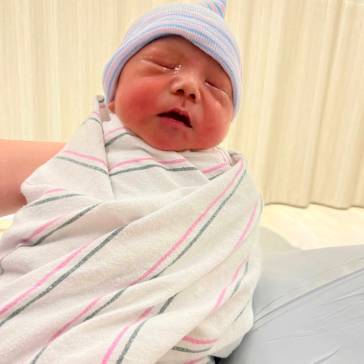 David is registered to the contest to win money with this photo: newborn, baby, infant, swaddled, blanket, hat, sleeping, hospital, wrapped, cute, child, person, soft_lighting, indoors, closeup, portrait, small, peaceful, newborn_hat, pink_stripes