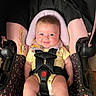 baby, car_seat, child, smile, safety_harness, yellow_clothing, infant, cute, happy, seatbelt, pink, black, pattern, indoors, portrait, toddler, head_support, bright_eyes, sitting, person