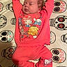 baby, sleeping, pajamas, pink_clothing, cartoon_characters, blanket, sugar_skulls, pattern, infant, cute, relaxed, indoors, child, face, feet, hands, soft_texture, resting, cozy, colorful
