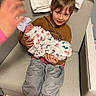 Luciana is registered to the contest to win money with this photo: child, baby, newborn, armchair, blanket, hospital, hat, boy, smile, clothing, human_hand, indoor, floor, pants, sitting, holding, person, footwear, fabric, hospital_room