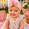 baby, child, flower_headband, pink_flower, blue_eyes, smiling, dress, floral_pattern, picnic_blanket, outdoor, grass, basket, pink_flowers, white_picket_fence, sign, sunlight, cute, portrait, happy, summer