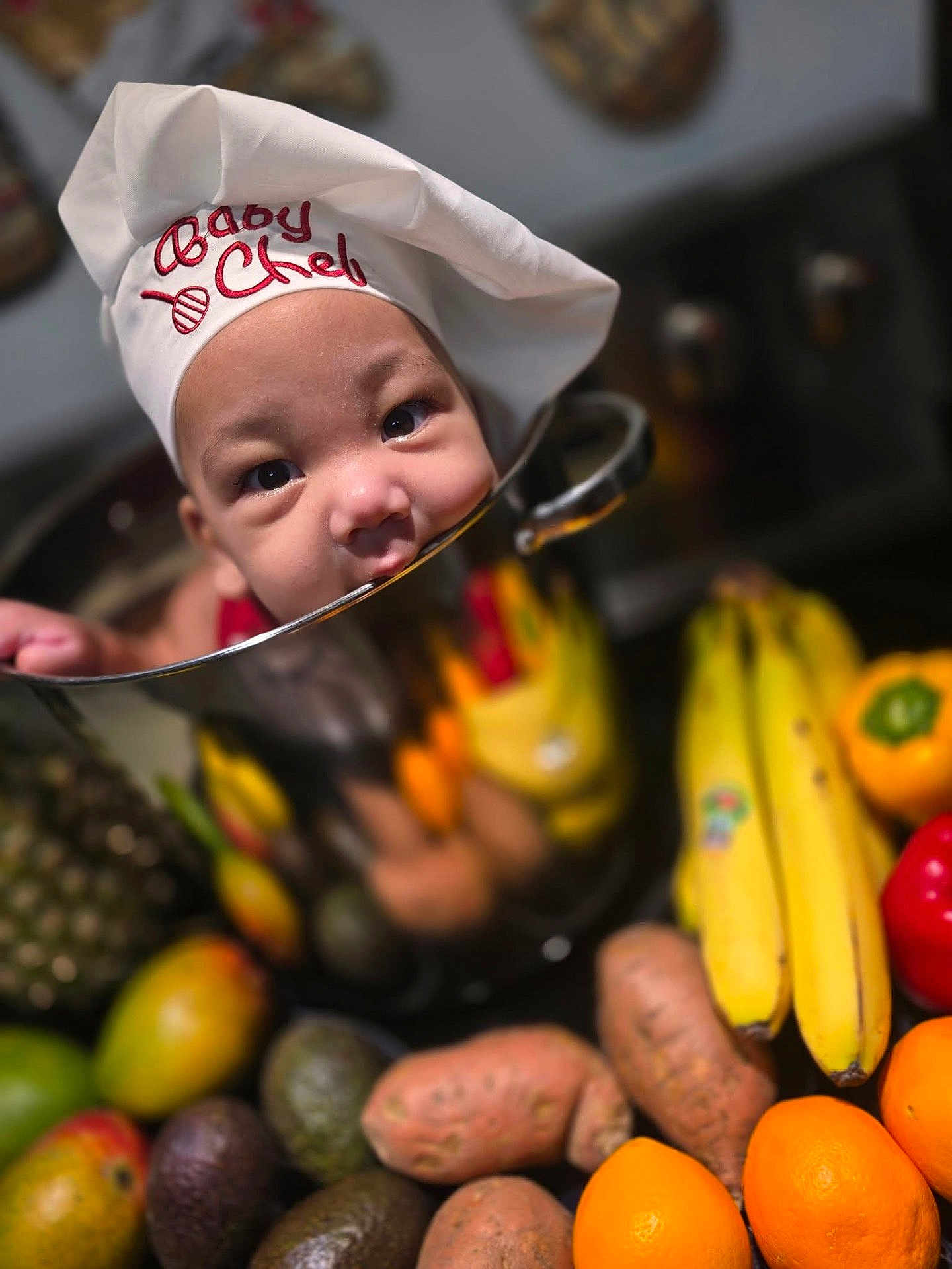 Jahdrian is registered to the contest to win money with this photo: baby, chef_hat, cooking_pot, fruit, vegetables, banana, orange, sweet_potato, avocado, pineapple, red_bell_pepper, yellow_bell_pepper, kitchen, reflection, cute, child, portrait, food, playful, gourmet