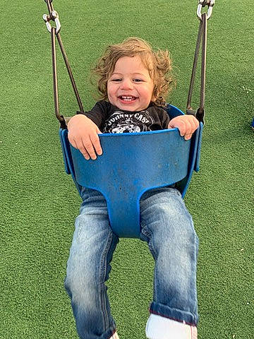 Amias is registered to the contest to win money with this photo: baby, baby_toddler_clothing, child, electric_blue, face, fun, grass, hair, happy, jeans, joy, leisure, outdoor_play_equipment, people_in_nature, person, photograph, playground, recreation, smile, swing