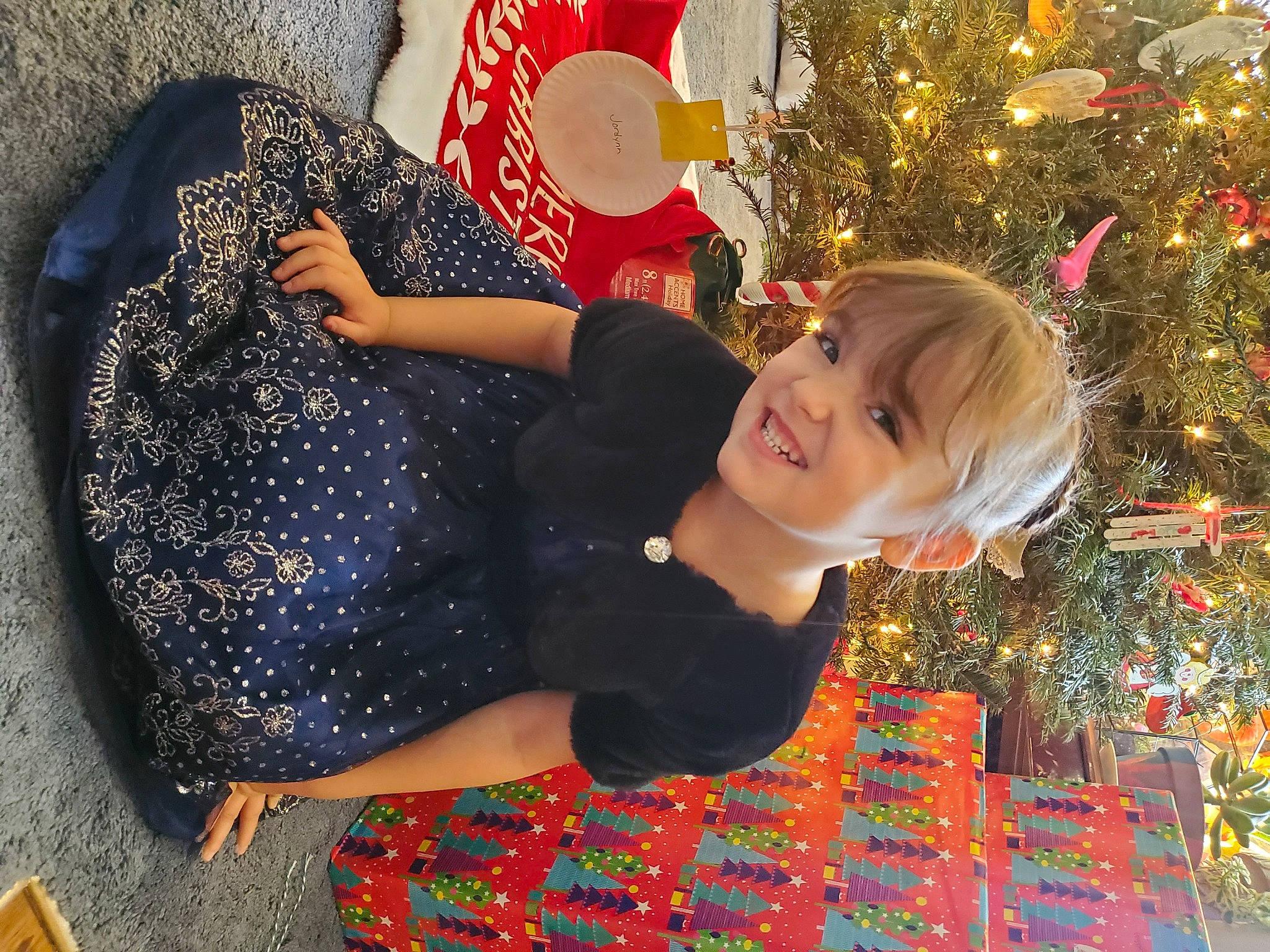 Jordynn is registered to the contest to win money with this photo: beauty, child, christmas_decoration, christmas_ornament, christmas_tree, event, facial_expression, fun, hairstyle, happy, holiday, holiday_ornament, human_body, joy, ornament, pattern, people_in_nature, person, red, sitting