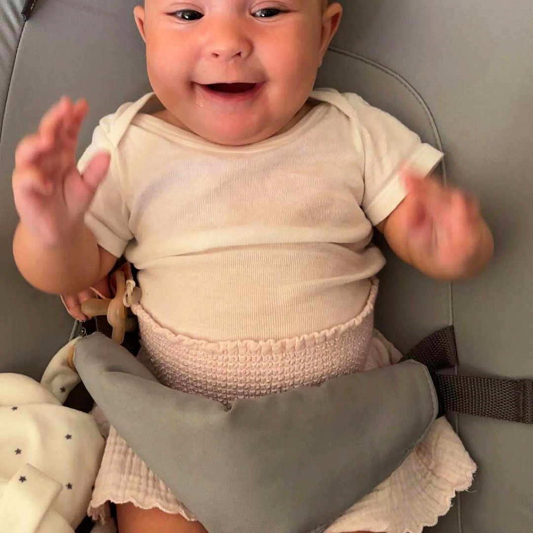 Nelya a rejoint le concours — aidez-le/la à gagner de superbes lots ! baby, baby_seat, child, clothing, cute, fabric, face, hands, happy, indoors, infant, joy, legs, person, pink_skirt, plush_toy, seatbelt, smiling, soft_toy, white_shirt