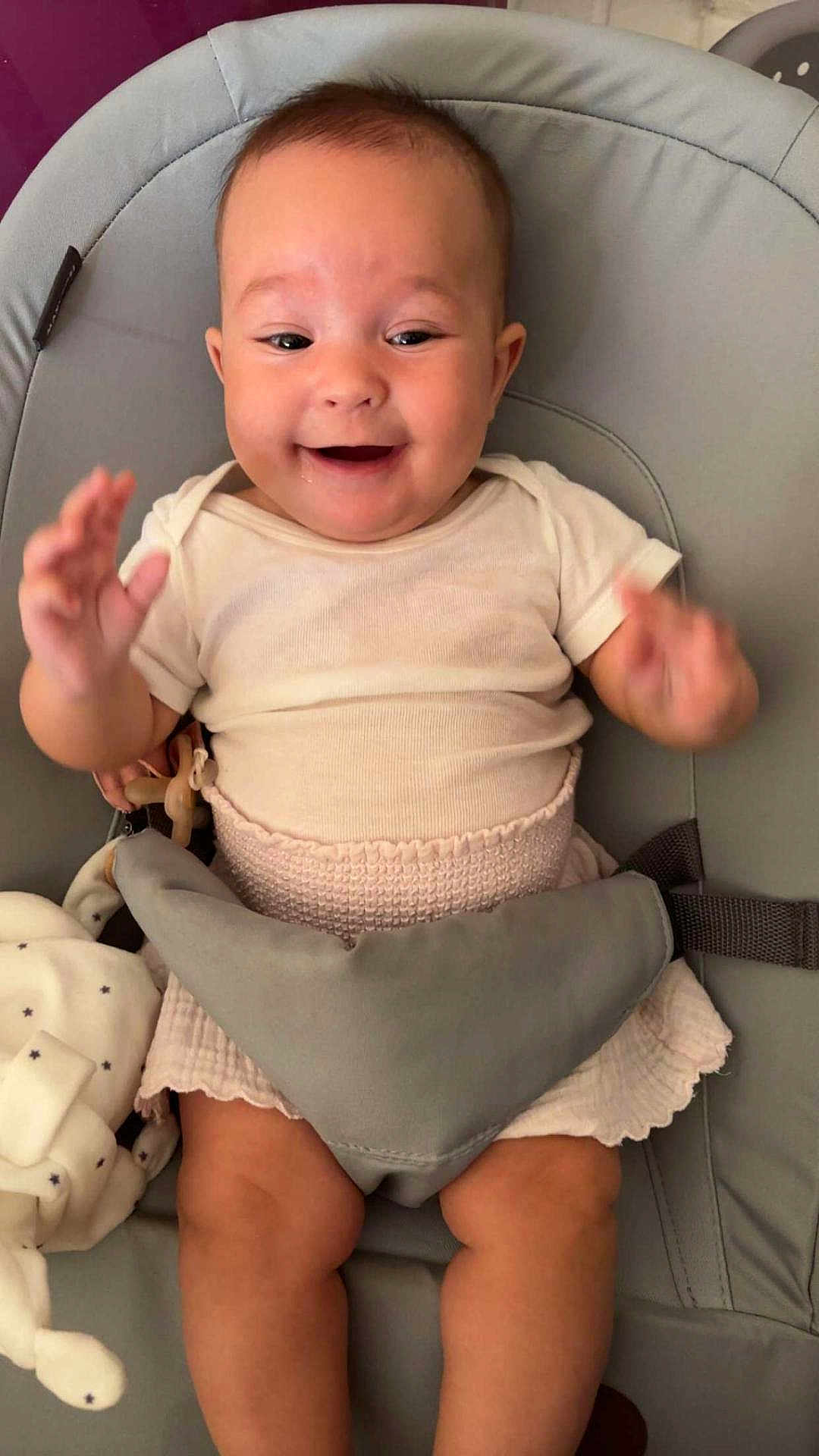 Nelya a rejoint le concours — aidez-le/la à gagner de superbes lots ! baby, smiling, happy, infant, baby_seat, clothing, white_shirt, pink_skirt, plush_toy, soft_toy, legs, hands, face, cute, indoors, child, seatbelt, fabric, person, joy