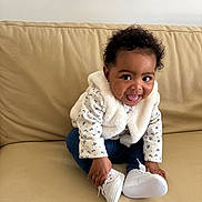 Ilayda a rejoint le concours — aidez-le/la à gagner de superbes lots ! adorable, baby, child, couch, curly_hair, dark_eyes, earrings, faux_fur_jacket, floral_pattern, happy, indoor, infant, jeans, playful, portrait, sitting, smile, sofa, tongue_out, white_shoes