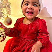 Ilayda a rejoint le concours — aidez-le/la à gagner de superbes lots ! baby, child, smiling, red_dress, santa_hat, christmas, ornament, holiday, festive, happy, indoor, face, cute, celebration, joyful, person, portrait, holiday_decoration, hand, bright