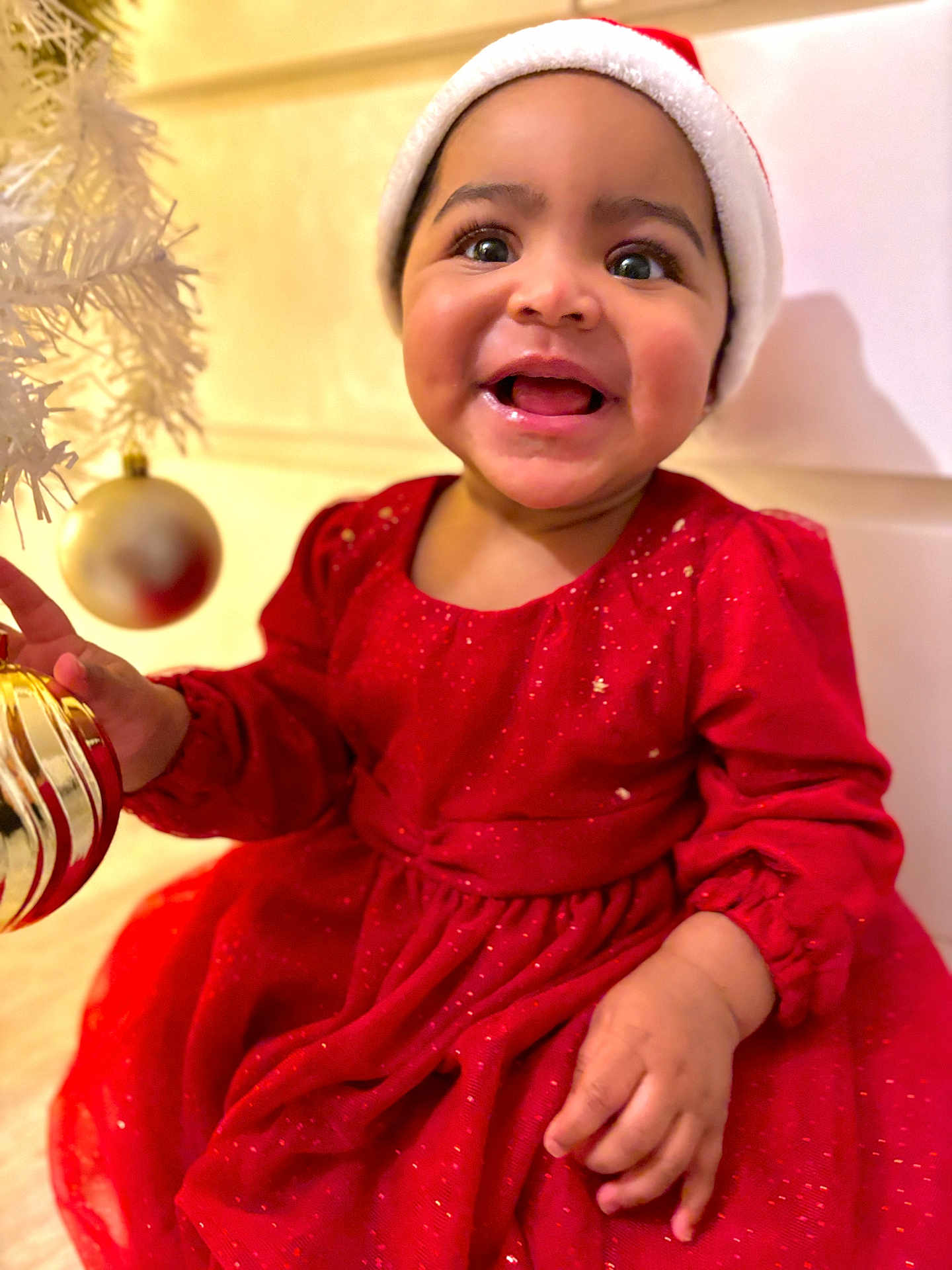Ilayda a rejoint le concours — aidez-le/la à gagner de superbes lots ! baby, child, smiling, red_dress, santa_hat, christmas, ornament, holiday, festive, happy, indoor, face, cute, celebration, joyful, person, portrait, holiday_decoration, hand, bright