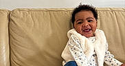 Ilayda participe au concours pour gagner de l'argent avec cette photo : baby, beige, child, clothing, couch, curly_hair, fur_vest, happy, indoor, infant, jeans, living_room, portrait, seated, skin, smile, sneakers, sofa, tiny_shoes, toyless