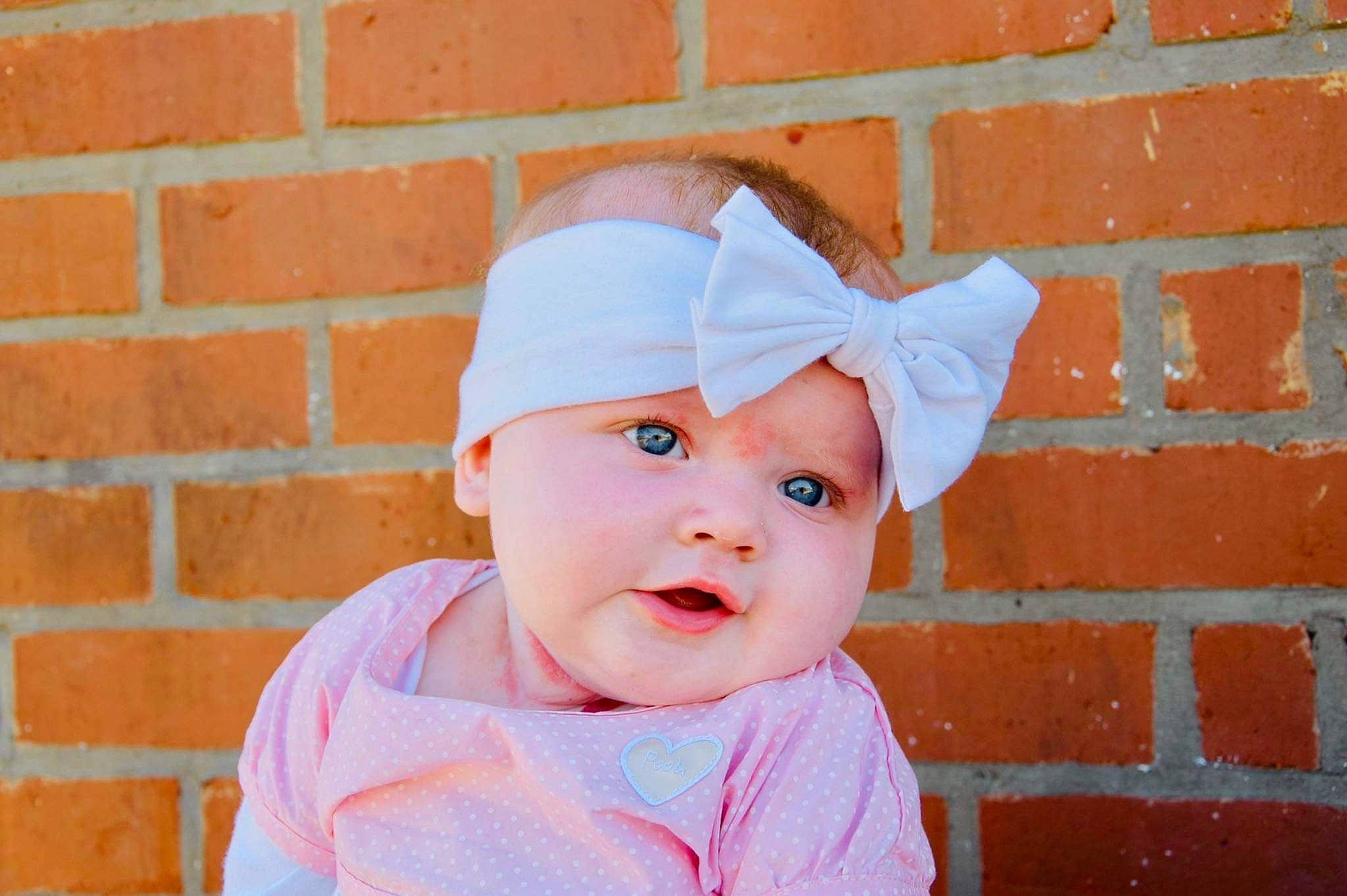 Alya participe au concours pour gagner de l'argent avec cette photo : baby, baby_toddler_clothing, beauty, brick, brickwork, cap, clothing, costume_hat, eye, face, happy, hat, headwear, lip, pattern, person, pink, skin, sleeve, street_fashion