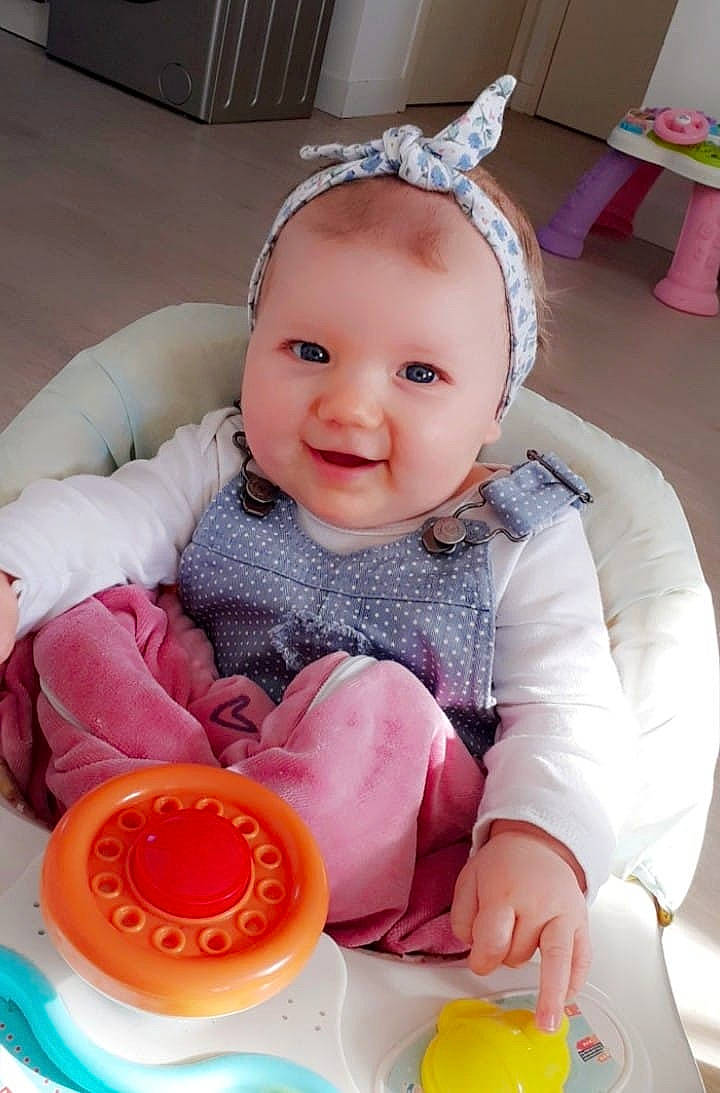 Capucine a rejoint le concours — aidez-le/la à gagner de superbes lots ! baby, baby_laughing, baby_products, baby_toddler_clothing, child, comfort, dishware, hair_accessory, headband, peach, person, pink, plate, serveware, sitting, toddler