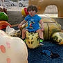 toddler, child, playground, sculpture, turtle, blue_clothing, mickey_mouse, outdoor, daylight, curly_hair, shoes, play_area, fence, palm_trees, toy, park, person, colorful, casual_clothing, young_child