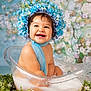 baby, child, smiling, flower_crown, blue_bonnet, milky_bath, clear_tub, water, greenery, floral_background, cute, happy, portrait, infant, sitting, skin, scarf, nature, innocence, studio_photo