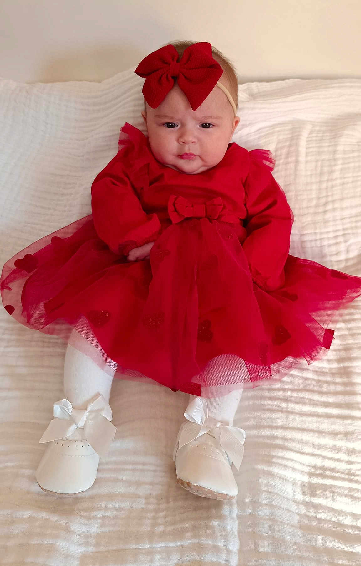 Ana Luiza a rejoint le concours — aidez-le/la à gagner de superbes lots ! baby, child, red_dress, headband, bow, white_shoes, white_tights, blanket, indoors, serious_expression, infant, cute, fashion, portrait, sitting, tulle_skirt, footwear, headwear, person, young_child