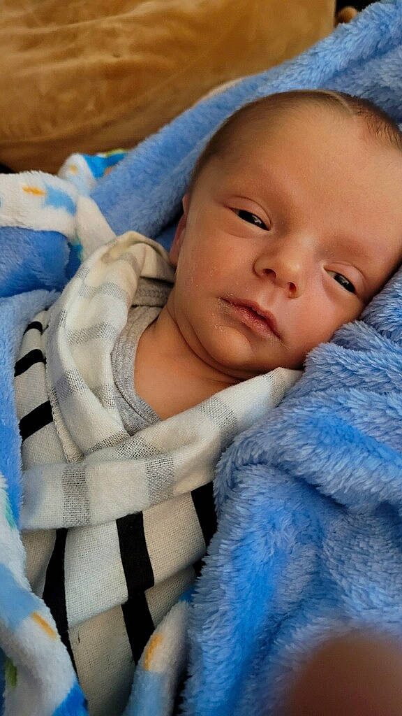 Tobias is registered to the contest to win money with this photo: azure, baby, baby_products, baby_toddler_clothing, blue, cap, cheek, child, comfort, electric_blue, eye, eyebrow, headgear, iris, linens, nose, outerwear, person, product, textile