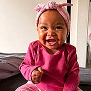 Mayanna joined the competition — help win amazing prizes! baby, child, infant, smiling, happy, portrait, pink_outfit, headband, bow, seated, bed, indoors, bedroom, closeup, face, curly_joy, dark_skin, fashion, playful, photography