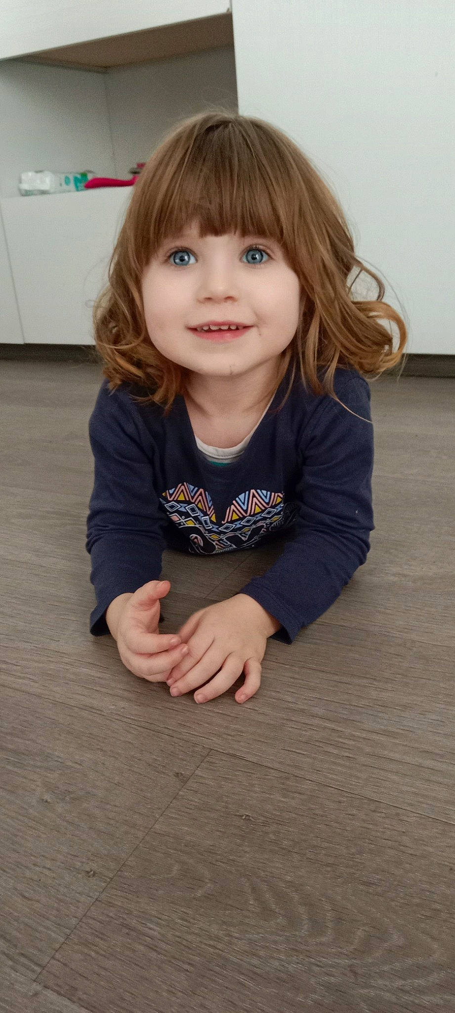 Louana a rejoint le concours — aidez-le/la à gagner de superbes lots ! baby_toddler_clothing, bangs, beauty, cheek, child, chin, face, facial_expression, floor, flooring, happy, hardwood, joy, lip, nose, person, sitting, skin, sleeve, smile