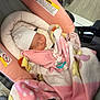 baby, newborn, infant, child, sleeping, car_seat, blanket, pink_blanket, hat, pacifier, cozy, soft_fabric, warning_label, fastening_strap, car_seat_handle, vehicle_interior, portrait, closeup, swaddle, sleeping_baby