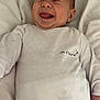 baby, infant, laughing, white_onesie, text_on_clothing, face, tongue_out, lying_down, blanket, cute, happy, skin, head, person, clothing, child, newborn, soft_texture, expression, smile