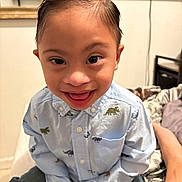 Aiden Solis is registered to the contest to win money with this photo: adult_arm, bed, bedroom, button_up_shirt, child, close_up, dinosaur_pattern, face, furniture, happy, home, indoors, open_mouth, photography, playful, portrait, seated, short_hair, smiling, toddler