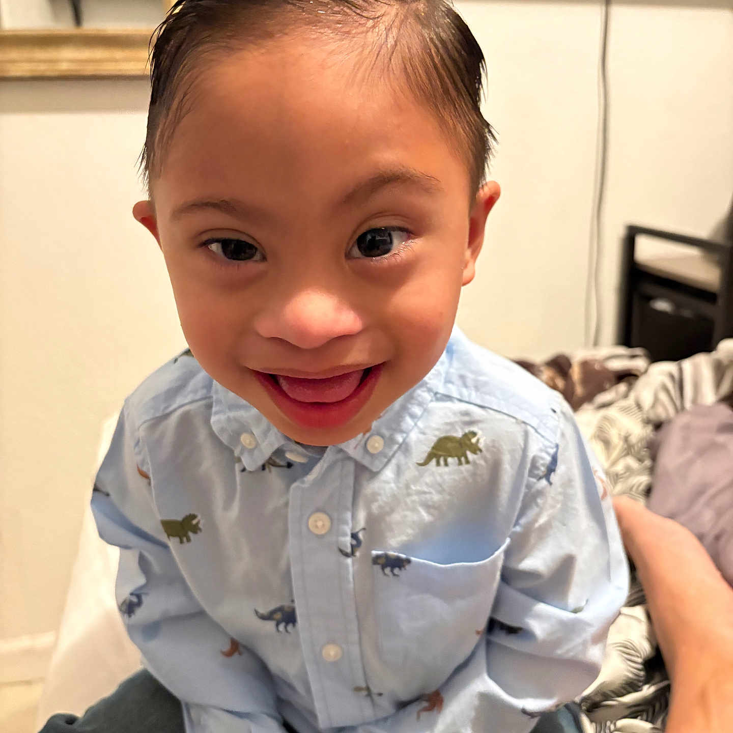 Aiden Solis is registered to the contest to win money with this photo: adult_arm, bed, bedroom, button_up_shirt, child, close_up, dinosaur_pattern, face, furniture, happy, home, indoors, open_mouth, photography, playful, portrait, seated, short_hair, smiling, toddler