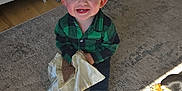 Chance is registered to the contest to win money with this photo: toddler, child, blue_eyes, green_shirt, plaid, blanket, rug, dog, indoor, smiling, happy, wooden_floor, cozy, pet, sunlight, home, socks, person, cute, playing