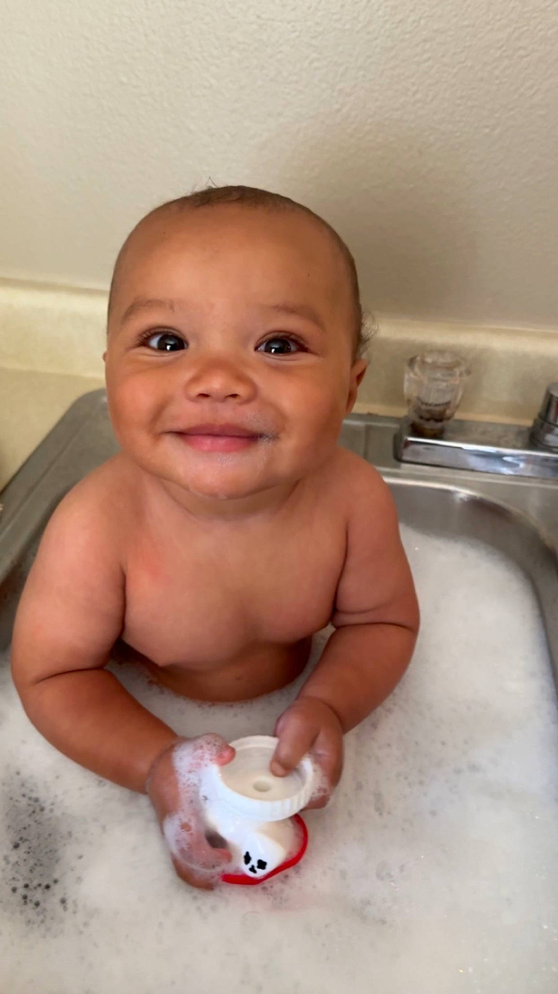 Kenai is registered to the contest to win money with this photo: baby, baby_bathing, bathing, bathroom, bathtub, cheek, chest, child, face, fluid, hand, joy, person, plumbing, plumbing_fixture, sink, skin, smile, tap, thumb