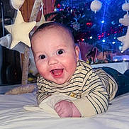 Elyo participe au concours pour gagner de l'argent avec cette photo : baby, blanket, blue_lights, bunny, child, christmas_tree, cute, face, festive, happy, holiday, indoor, infant, lights, plush_toys, smiling, star, striped_shirt, toy_mobile, wood_paneling