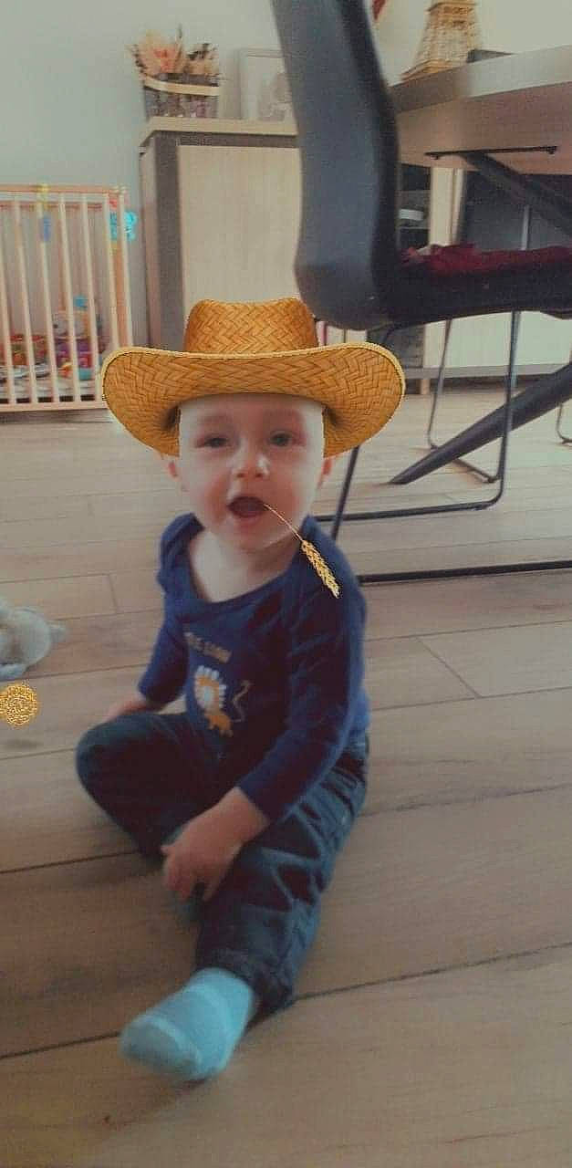 Hugo participe au concours pour gagner de l'argent avec cette photo : baby, baby_toddler_clothing, cap, child, eye, fashion_accessory, fedora, floor, flooring, fun, hardwood, hat, headwear, person, play, sitting, sun_hat, toddler, varnish, wood