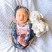 Gracie joined the competition — help win amazing prizes! newborn, baby, infant, sleeping, blanket, headband, floral, wrapped, stuffed_animal, plush, lamb, ribbon, soft, white, texture, peaceful, cute, portrait, indoors, child
