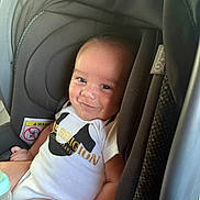 Jesus joined the competition — help win amazing prizes! baby, child, infant, smiling, portrait, car_seat, harness, vehicle, indoors, sitting, face, eyes, white_clothing, bodysuit, bottle, padded_seat, travel, close_up, happy, safe