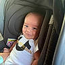 baby, child, infant, smiling, portrait, car_seat, harness, vehicle, indoors, sitting, face, eyes, white_clothing, bodysuit, bottle, padded_seat, travel, close_up, happy, safe