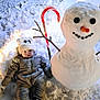 baby, button_eyes, candy_cane, carrot_nose, child, cold_weather, cozy, face, hat, holiday, mittens, outdoor, playful, smile, snow, snowman, snowy_ground, stick_arms, winter, winter_clothing