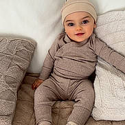 Kahïm participe au concours pour gagner de l'argent avec cette photo : baby, child, pajamas, hat, smile, couch, pillow, blanket, indoor, cozy, cute, infant, sitting, soft, comfortable, person, young, warm, relaxed, home