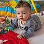 baby, infant, child, tummy_time, toy, play_mat, colorful_pillow, red_blanket, jacket, big_eyes, face, hand, plush_toy, rattle, indoor, carpet, wooden_floor, photogenic, cute, portrait