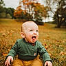 baby, child, sitting, outdoor, grass, fall, autumn, leaves, green_shirt, mustard_pants, happy, excited, nature, field, trees, portrait, young_child, casual_clothing, seasonal, daylight