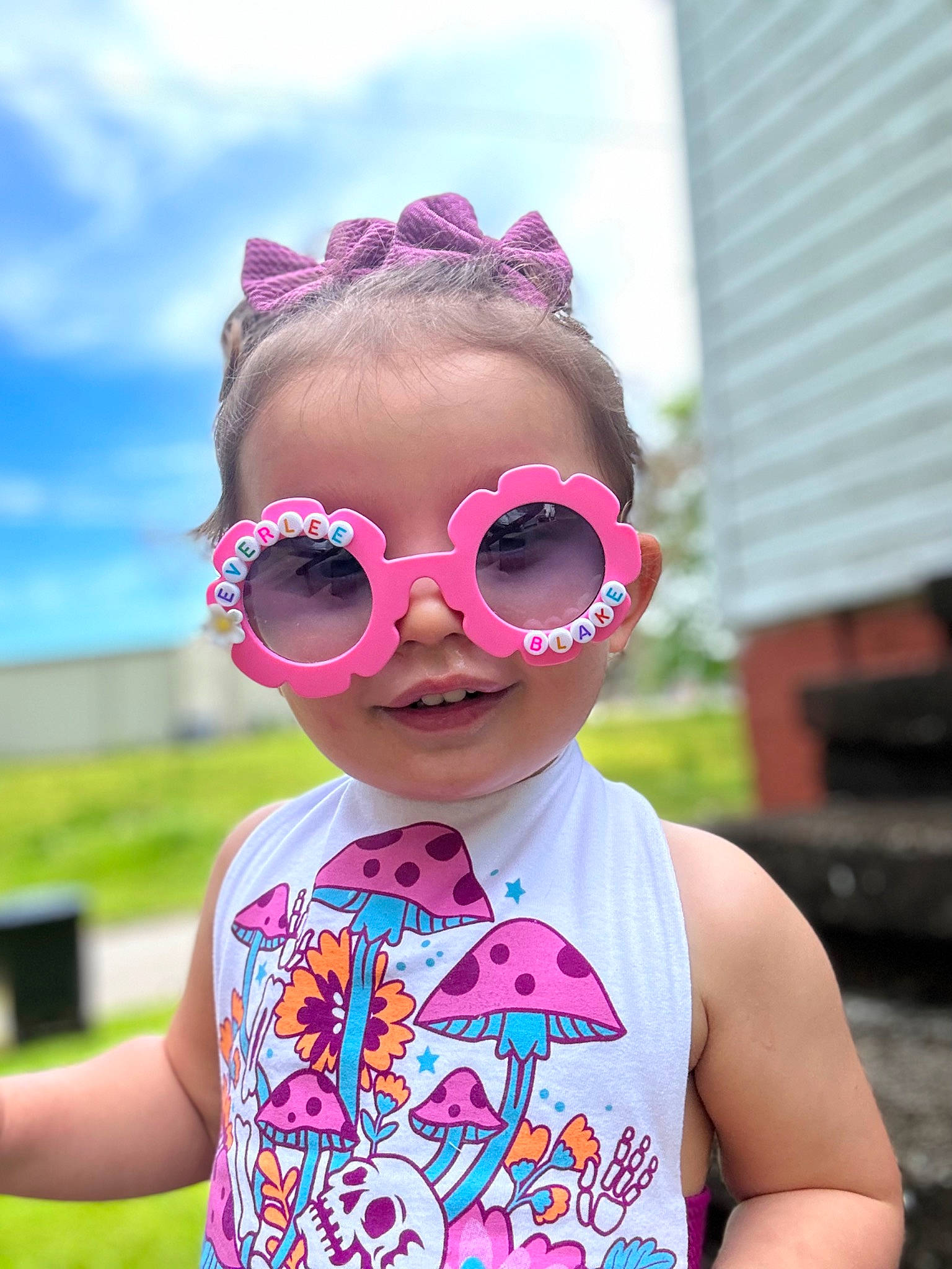 Everlee is registered to the contest to win money with this photo: baby_toddler_clothing, cool, eyewear, face, glasses, goggles, grass, happy, leisure, lip, magenta, neck, person, personal_protective_equipment, pink, plant, sky, smile, sunglasses, toddler